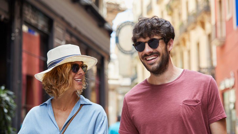 Homem e mulher passeiam na rua com óculos de sol