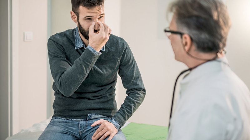Homem com septo nasal desviado fala com médico sobre septoplastia