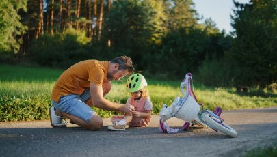 Pai ajuda filha que se magoou ao cair da bicicleta.