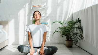 Mulher sentada no chão, de pernas cruzadas, a fazer meditação, praticando o autocuidado